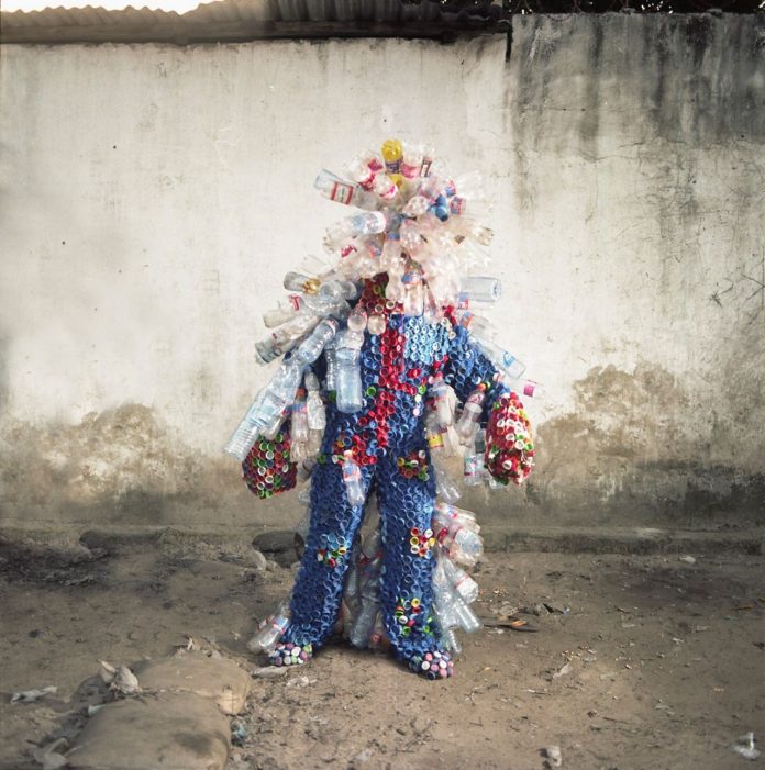 Artist Junior Mungongu wears a costume made out of plastic bottles and lids.